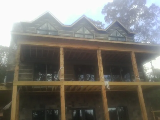 Dormers and porch framing on a large log home under construction — Roof Coating work by our crew in Georgetown